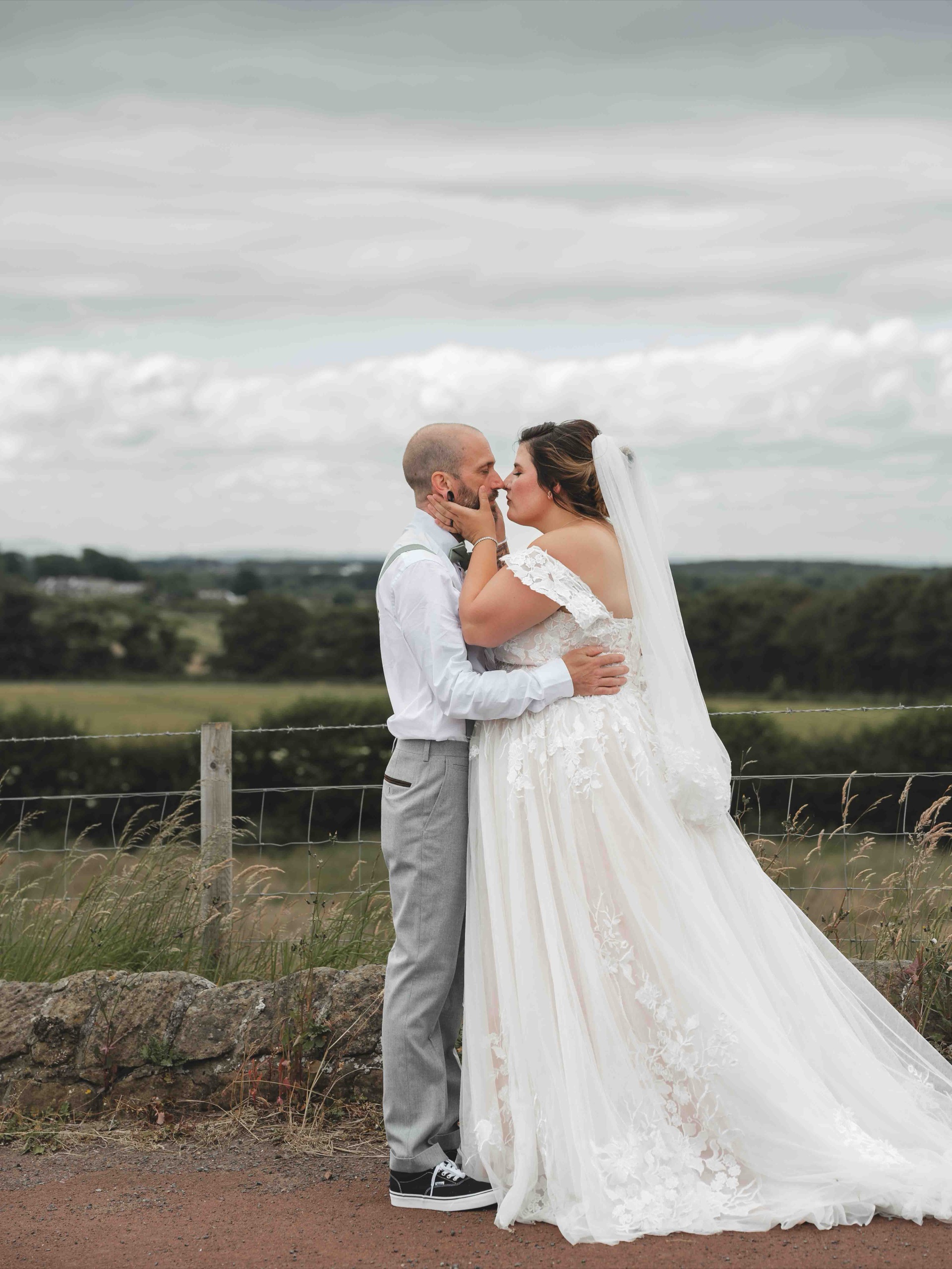 Cessca and Tony sharing a kiss with the rolling countryside behind them