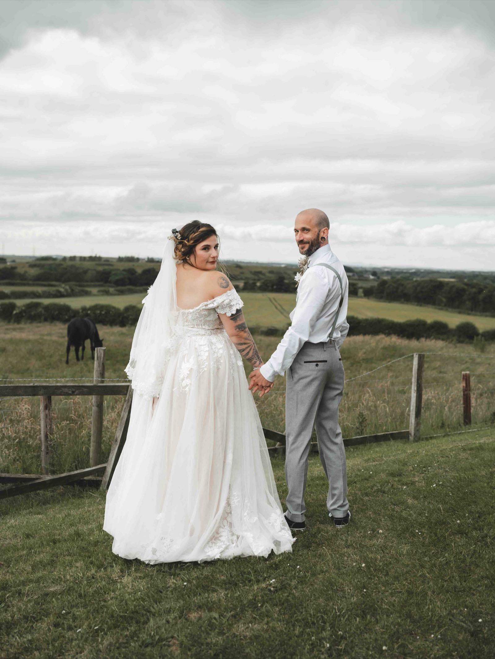 Cessca and Tony walking hand in hand along a country lane, looking back at the camera