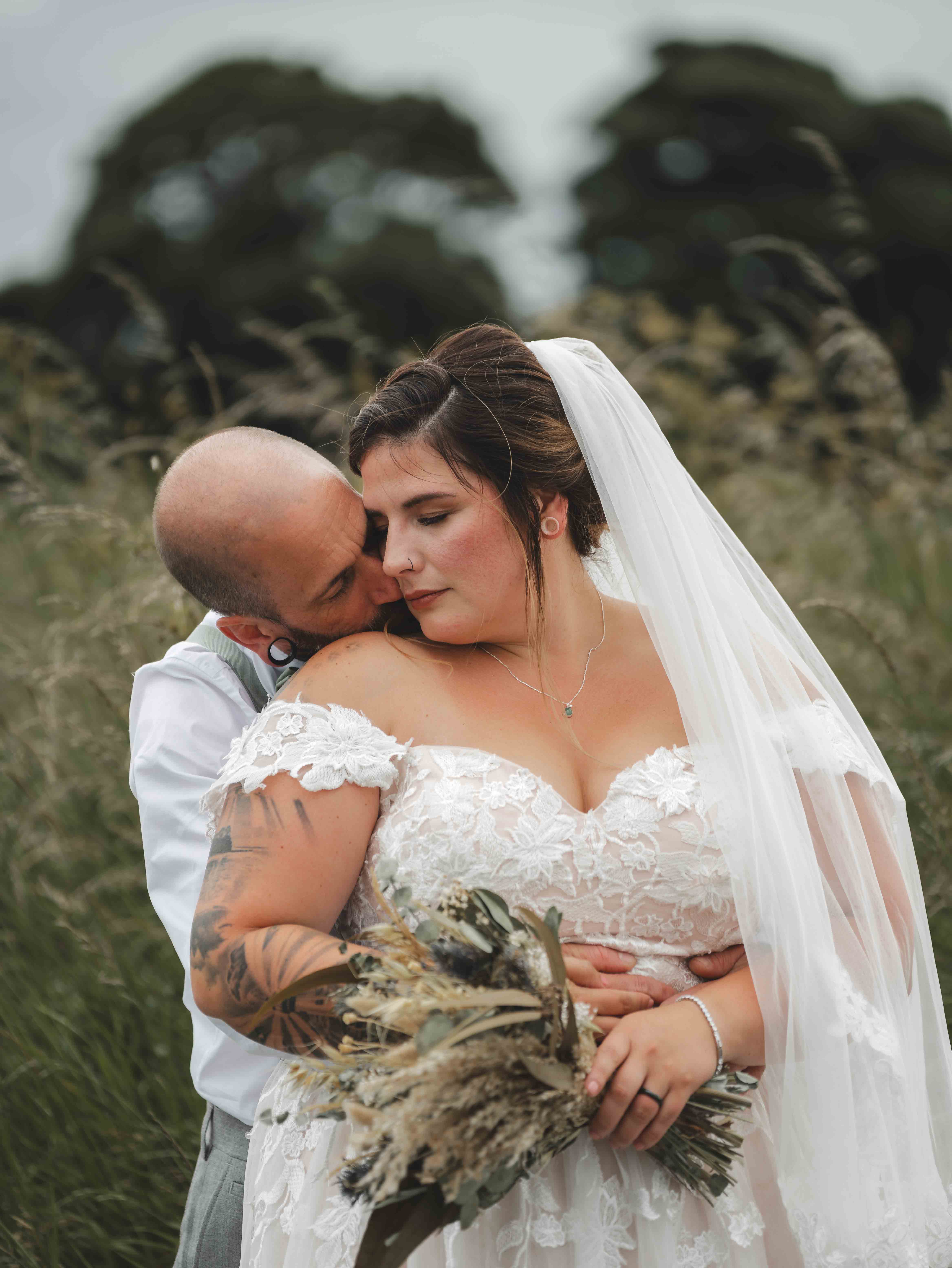 Cessca and Tony sharing an intimate embrace in a tall grass field during golden hour