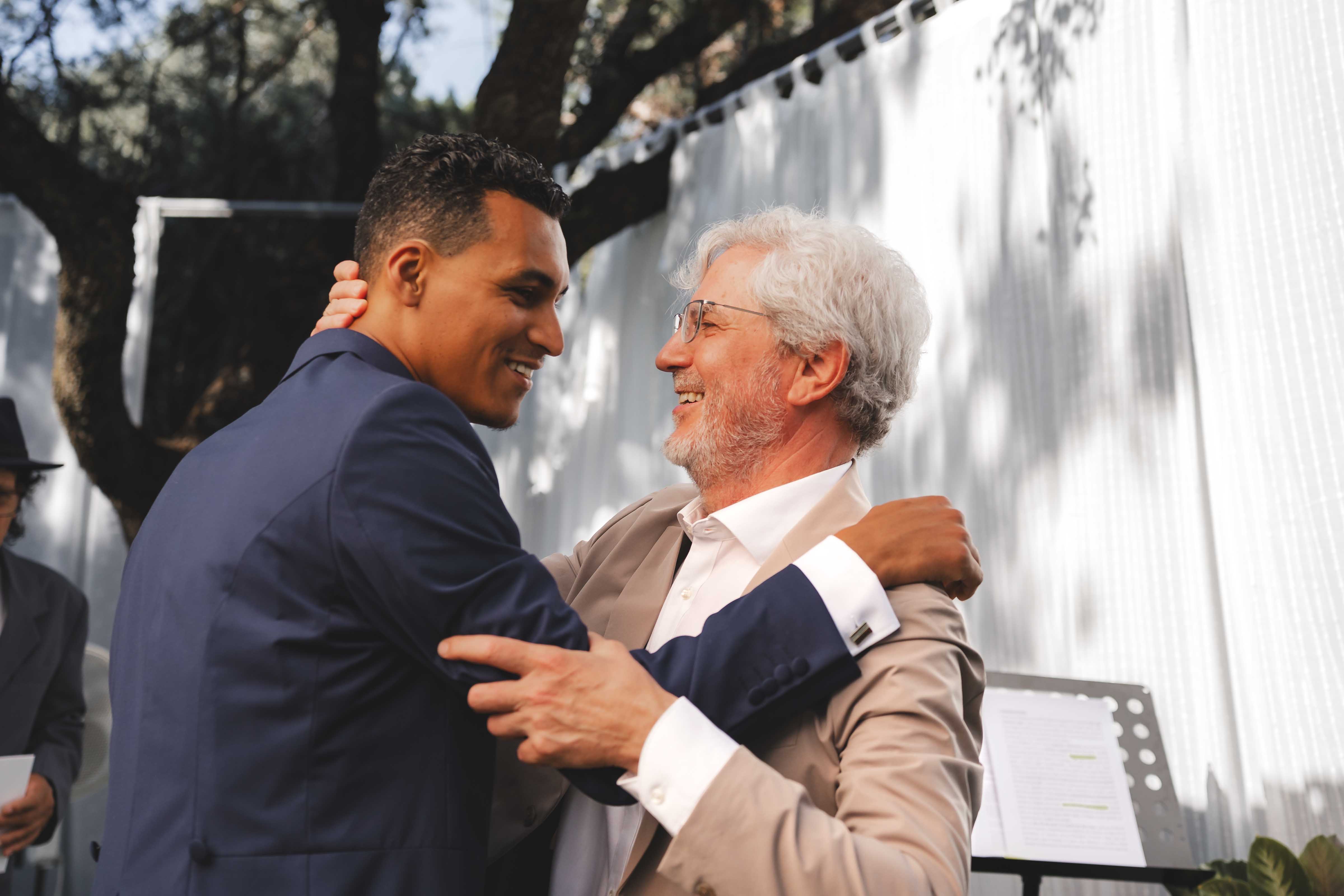Leo sharing a warm embrace with a family member during the ceremony, both smiling
