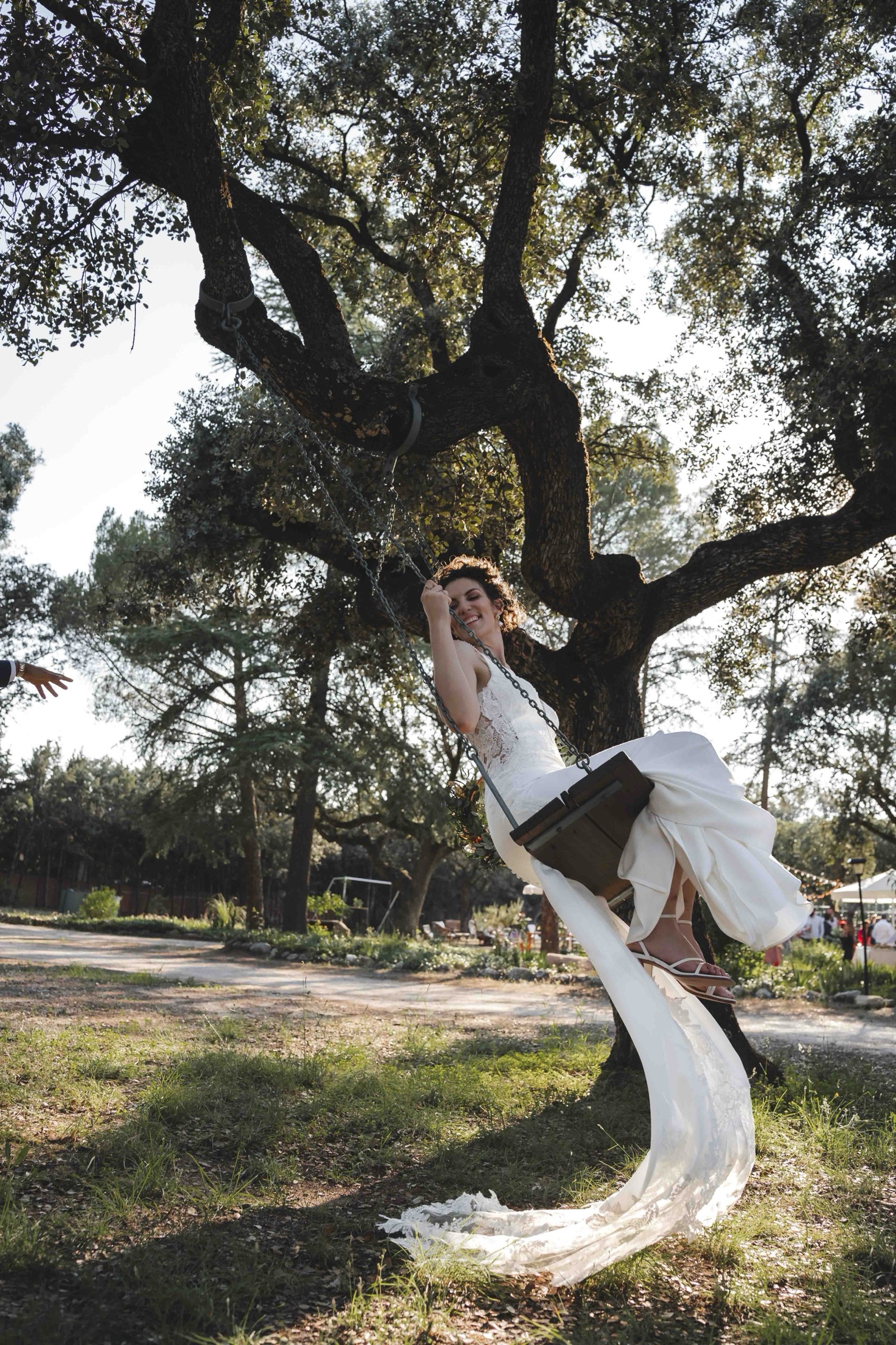 Maria laughing on a wooden swing beneath a large oak tree, her dress flowing in the breeze
