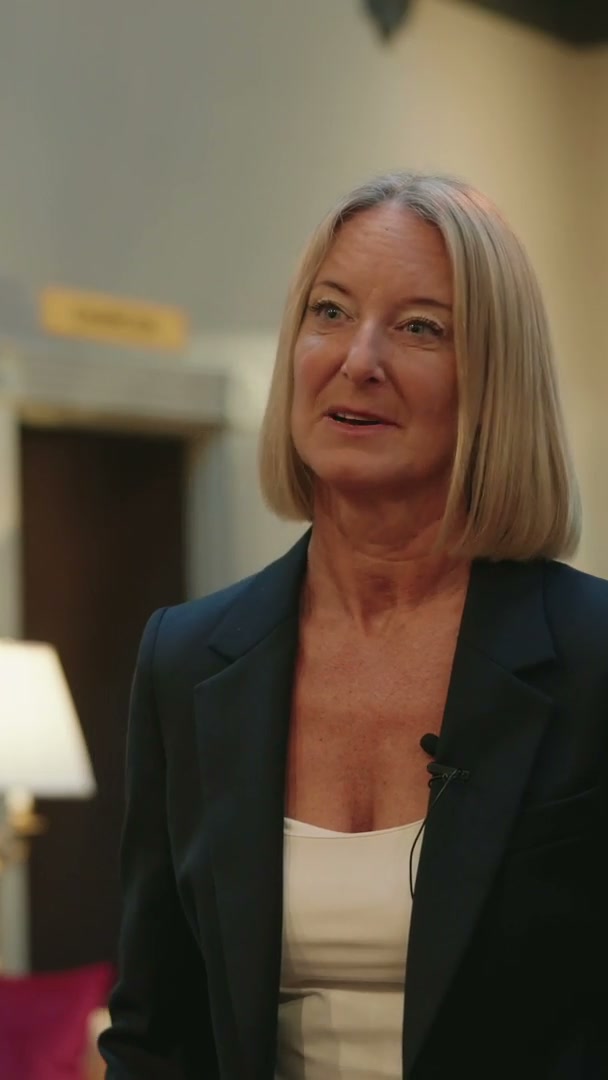 A business leader in a navy blazer speaking on camera